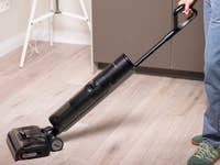 Eine Person verwendet einen Dreame H15 Pro Staubsauger auf einem Holzboden.