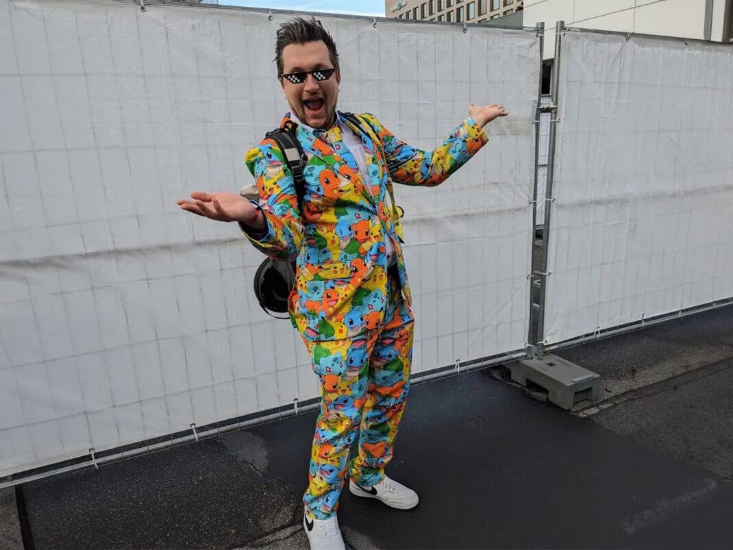 Eine Person steht vor einem Zaun in einem Pokemon-Anzug