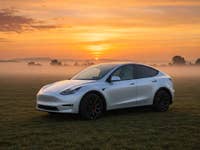 Tesla Model Y im Sonnenaufgang in der Seitenansicht.