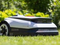 Ecovacs Goat A1600 RTK Rasenmäher auf Gras mit Grün im Hintergrund.