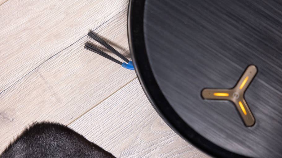 Nahaufnahme des Ecovacs Deebot X9 Pro Omni Saugroboters mit sichtbaren Bürsten und dem Fell eines schwarzen Haustiers in der Nähe.