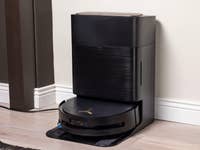 Ein schwarzer Ecovacs Deebot X9 Pro Omni-Roboterstaubsauger und seine Dockingstation in einem modernen Innenraum.