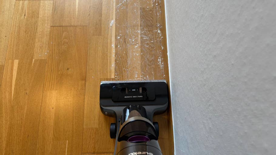 Eureka RapidWash 730 Mehl reinigt einen Holzboden in der Nähe einer Wand.