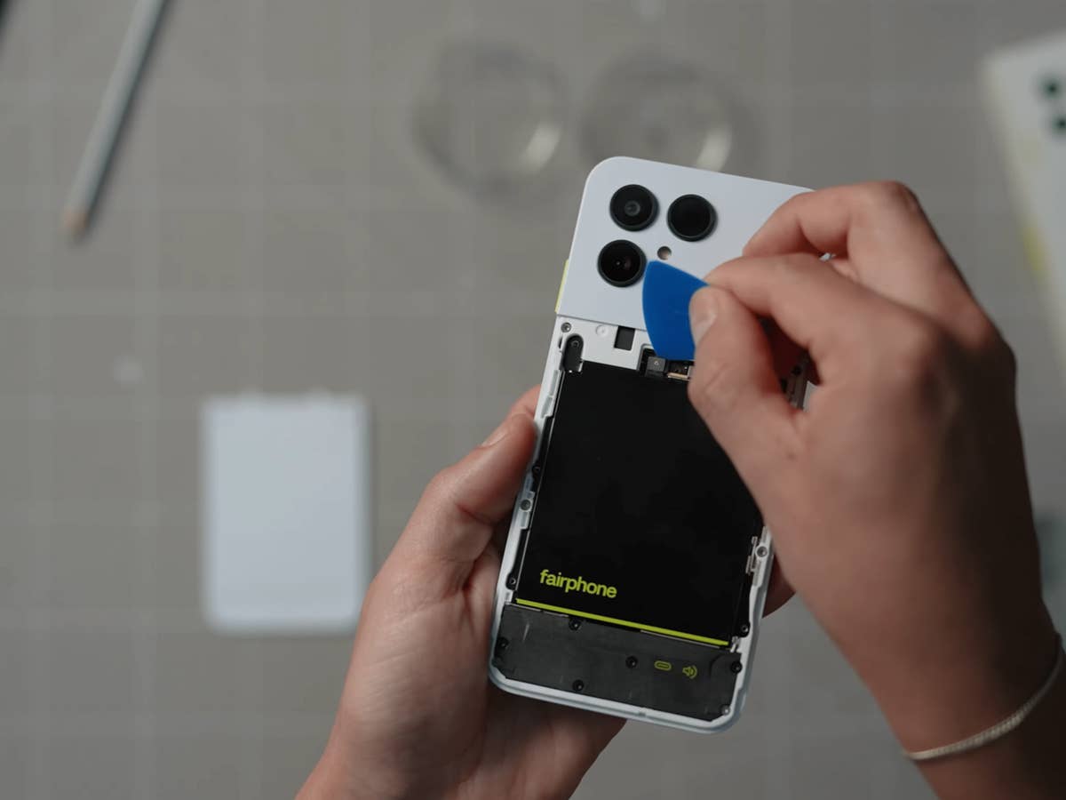 Eine Person verwendet ein Werkzeug, um die Rückseite eines Fairphone 6-Smartphones zu öffnen und die Batterie sichtbar zu machen.