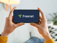 Eine Person hält ein Smartphone mit dem freenet-Logo.