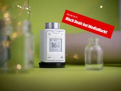 Das Fritz!Dect 302 smarter Heizkörperregler vor grünem Hintergrund mit roten Banner