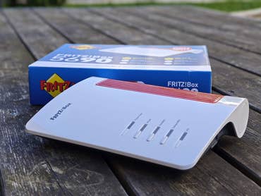Fritz!Box 5690 Router auf einer Holzoberfläche mit der Verpackung im Hintergrund.