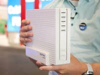 Eine Person hält ein Fritz!Box 6690 Pro Kabelmodem mit mehreren Tasten an der Seite.