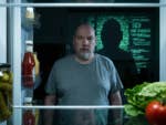 Casi schaut in den offenen Kühlschrank, hinter ihm eine Silhouette aus Code im Matrix-Stil.