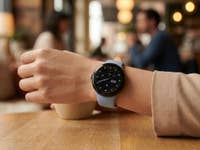 Eine Google Pixel Watch 4 an einem Handgelenk einer Frau in einem Café