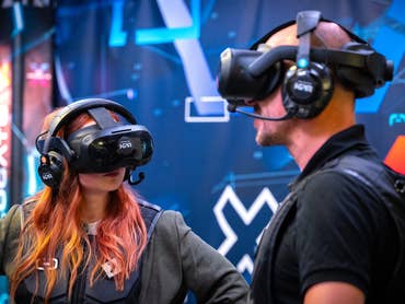 Zwei Personen mit VR-Headsets erleben eine virtuelle Realität vor einem digitalen Hintergrund.