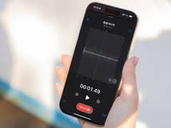 Eine Hand hält ein Apple iPhone 16 Pro, das einen Sprachaufnahmebildschirm mit Wellenform und Timer anzeigt.