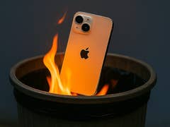 Ein iPhone, das teilweise in Flammen in einem Mülleimer steckt.