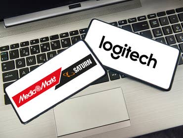 MediaMarkt/Saturn- und Logitech-Logo auf Smartphones, die auf einem Laptop liegen.