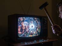 Mann schlägt mit Hammer auf Fernseher