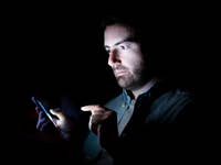 Mann mit Smartphone in einem dunklen Raum