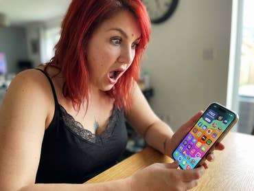 Eine Frau sieht erstaunt auf ihr Handy, wo viele kostenlose Apps angeboten werden.