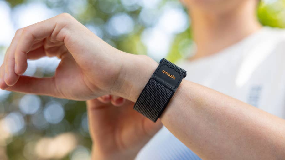 Nahaufnahme einer Hand mit einem Amazfit Helio-Armband am Handgelenk, vor unscharfem Hintergrund im Freien.