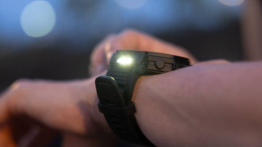 Eine Nahaufnahme einer Amazfit T-Rex Pro 3 Smartwatch am Handgelenk, bei schwachem Licht beleuchtet.