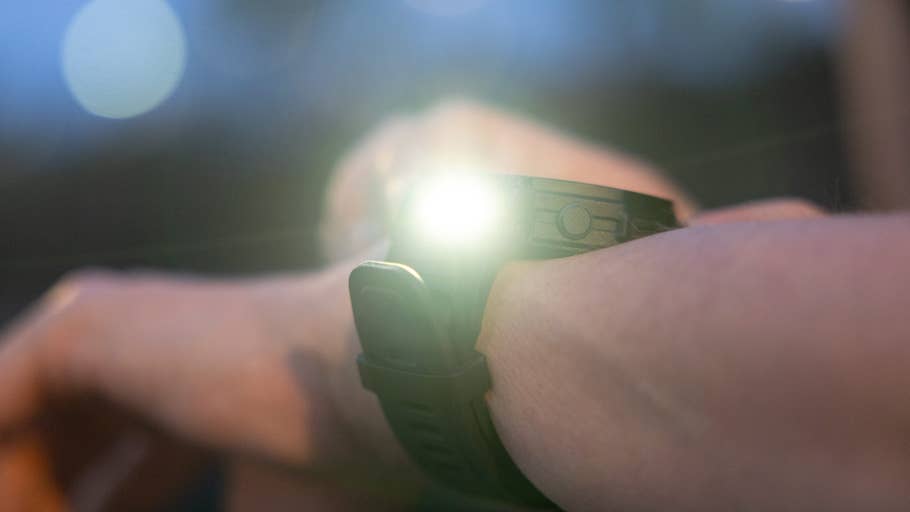 Nahaufnahme einer Amazfit T-Rex Pro 3 Smartwatch, die ein helles Licht an einem Handgelenk zeigt.