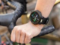 Eine Hand mit einer Amazfit T-Rex Pro 3-Smartwatch am Fahrradlenker, die Uhrzeit und Fitnessdaten anzeigt.