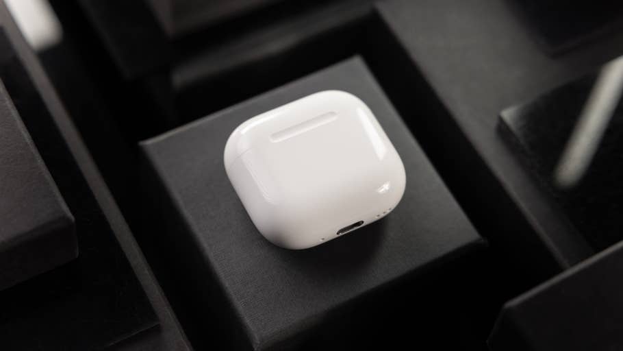 Ein Paar weiße Apple AirPods auf einer schwarzen Oberfläche.