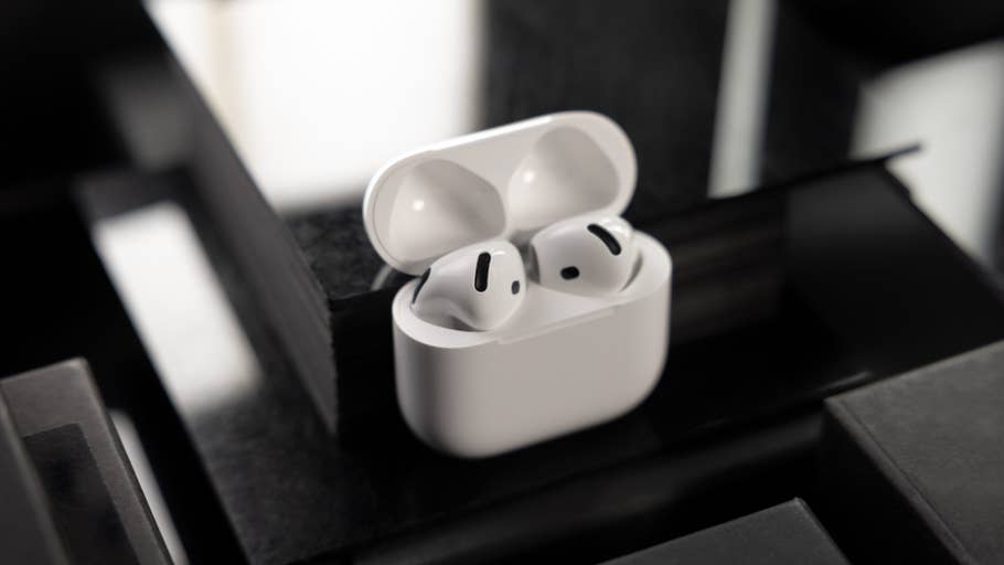 Ein Paar Apple AirPods in ihrem Ladecase, auf einer dunklen Oberfläche platziert.