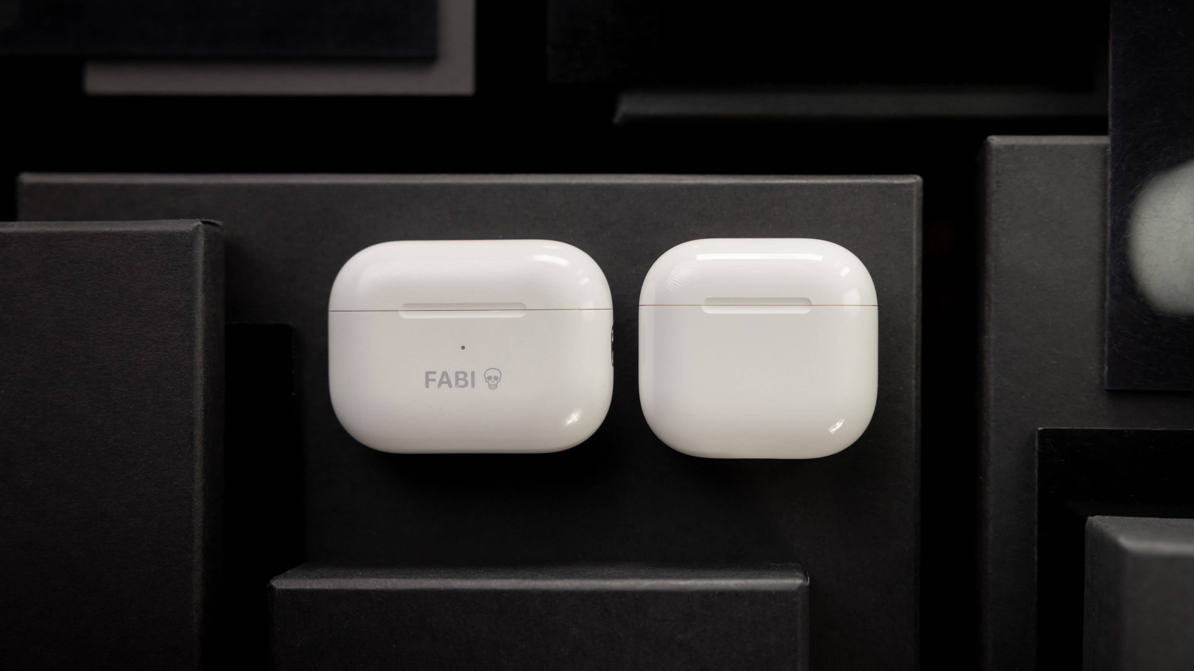 Weiße Apple AirPods-Hüllen auf dunklem Hintergrund, eine mit 'FABI'-Text.