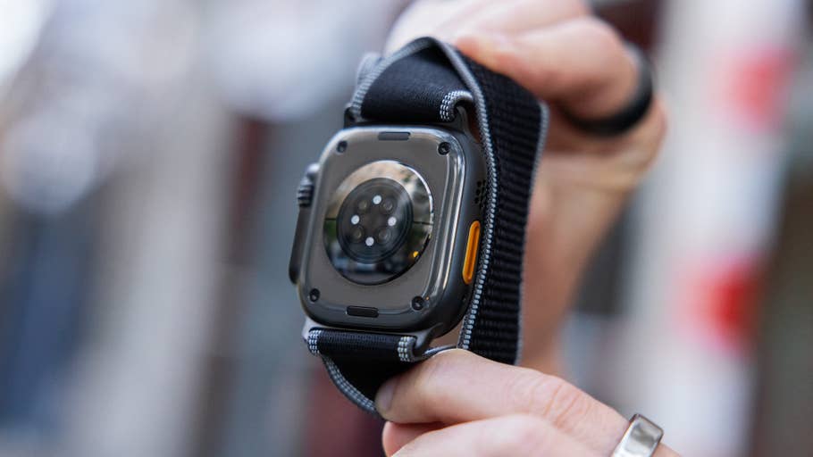 Eine Person hält die Rückansicht einer Apple Watch 3 Ultra mit einem schwarzen Armband.