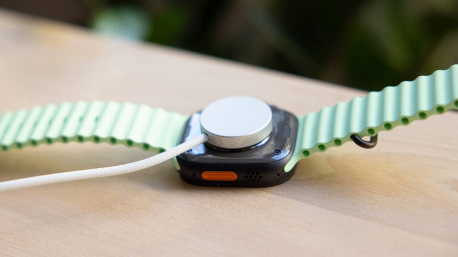 Nahaufnahme einer Apple Watch Ultra 3 mit grünem Armband, das die Rückseite und den Ladeanschluss zeigt.