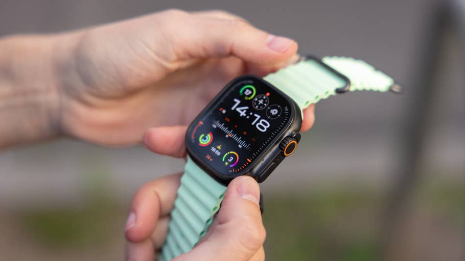 Eine Person hält eine Apple Watch 3 Ultra, die die Uhrzeit, Fitnessmetriken und bunte App-Icons anzeigt.