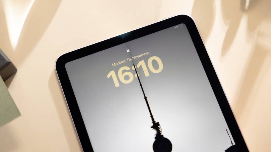 Apple iPad Mini 7 zeigt die Uhrzeit 16:10 auf einem Sperrbildschirm mit der Silhouette eines Turms.