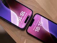 Zwei iPhones zeigen die Uhrzeit: 18:15 und 18:13 auf einer Holzoberfläche.