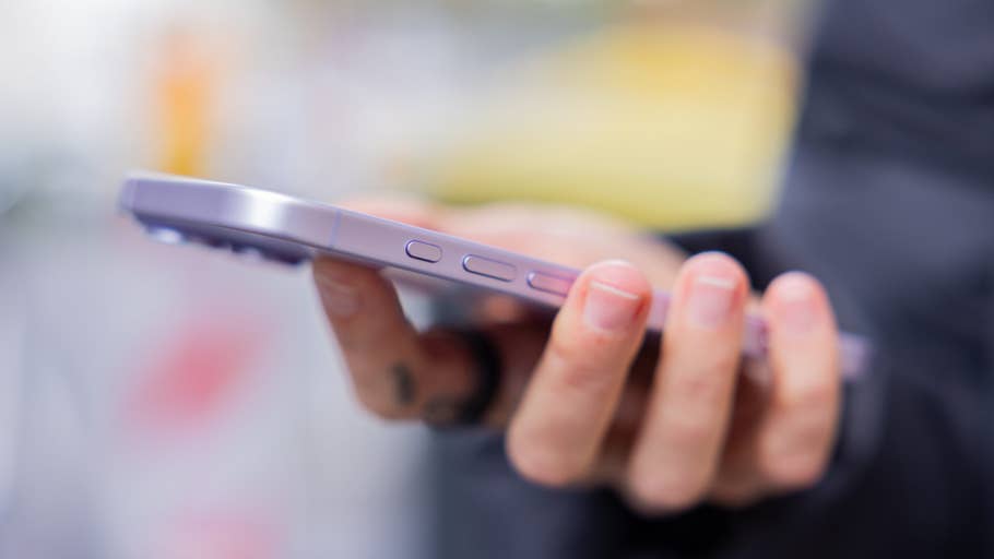 Eine Person hält ein lila iPhone 17, das die Seitentasten und einen verschwommenen Hintergrund zeigt.