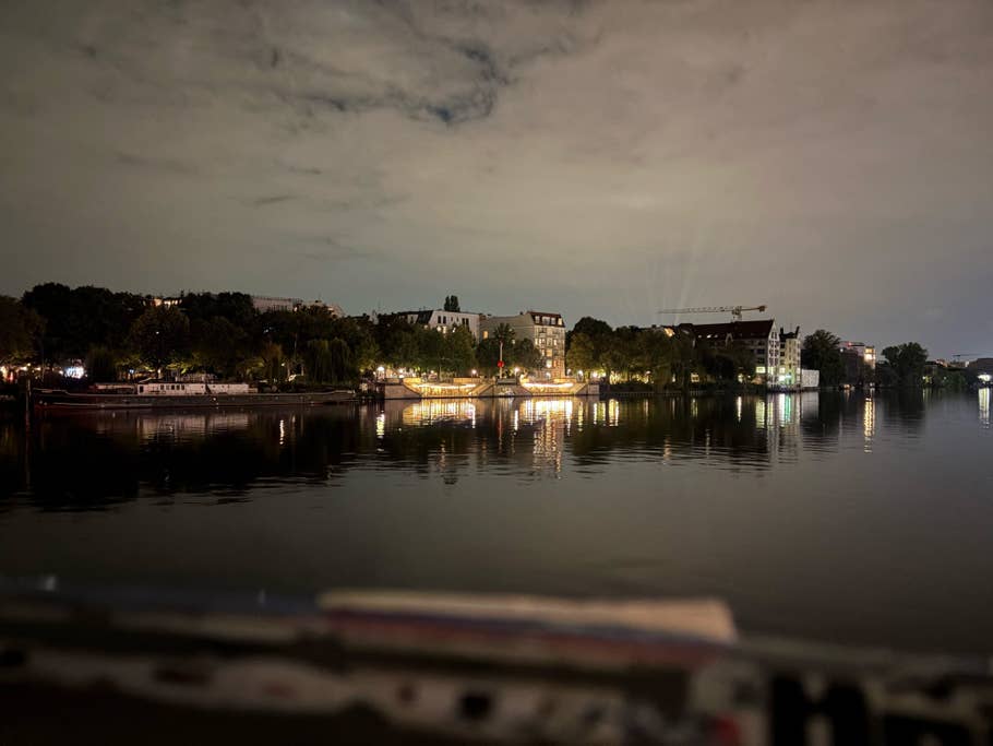 Eine ruhige Nachtszene eines Flusses mit beleuchteten Gebäuden, die sich im Wasser spiegeln.