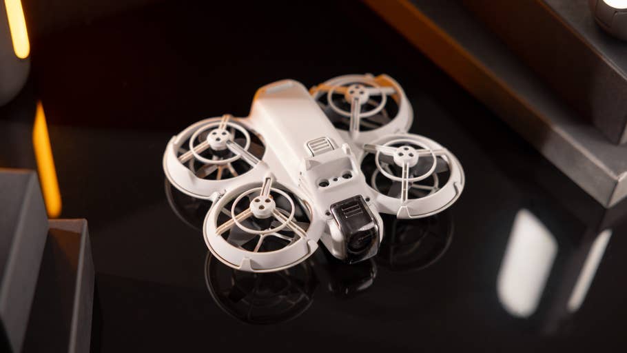 Eine weiße Drohne mit vier schützenden Propellern auf einer dunklen Oberfläche.