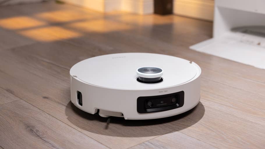 Ein runder weißer Saugroboter auf einem Holzboden.