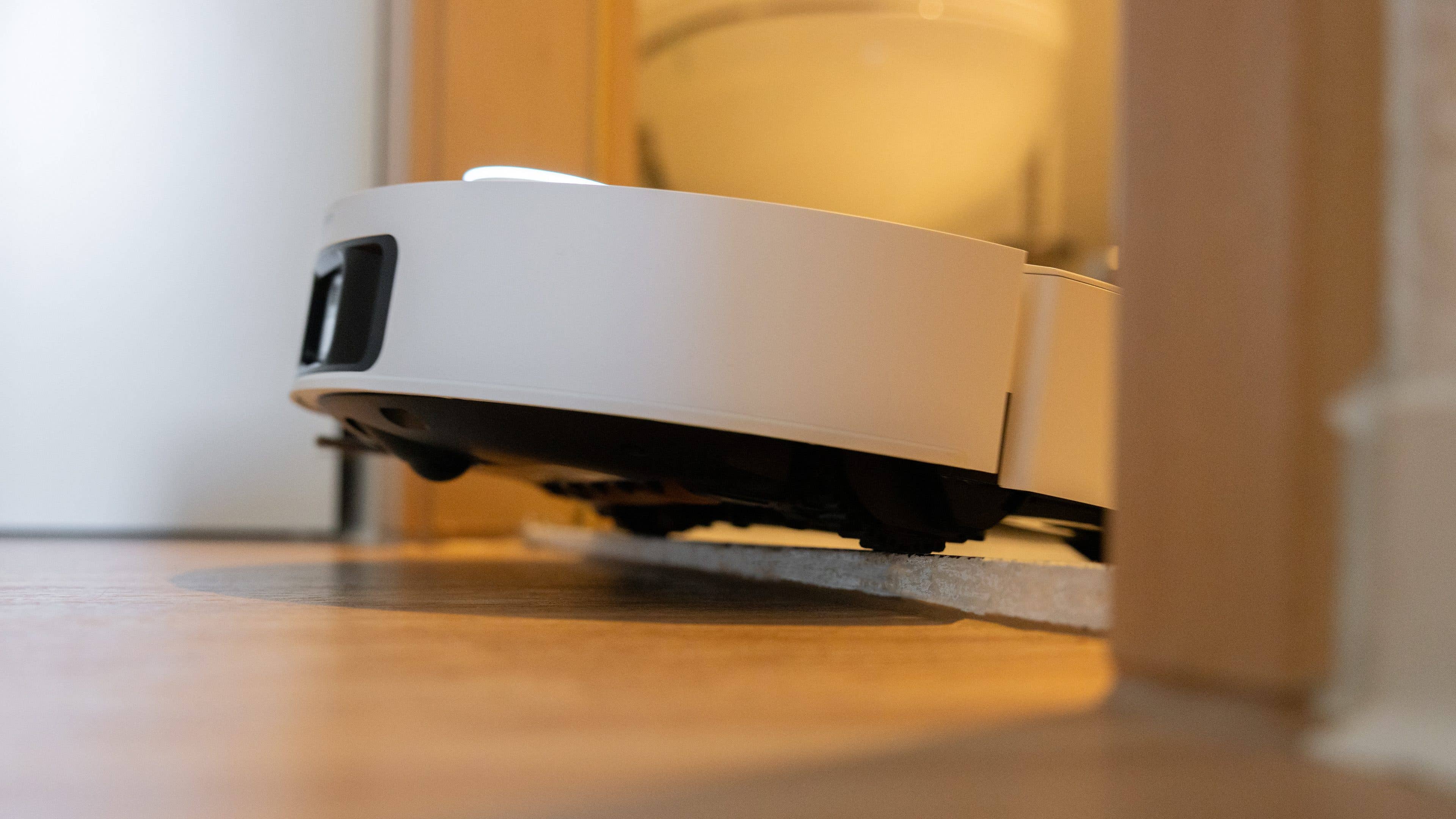 Eine Nahaufnahme des Dreame X50 Ultra Saugroboters, der auf einem Holzboden navigiert.