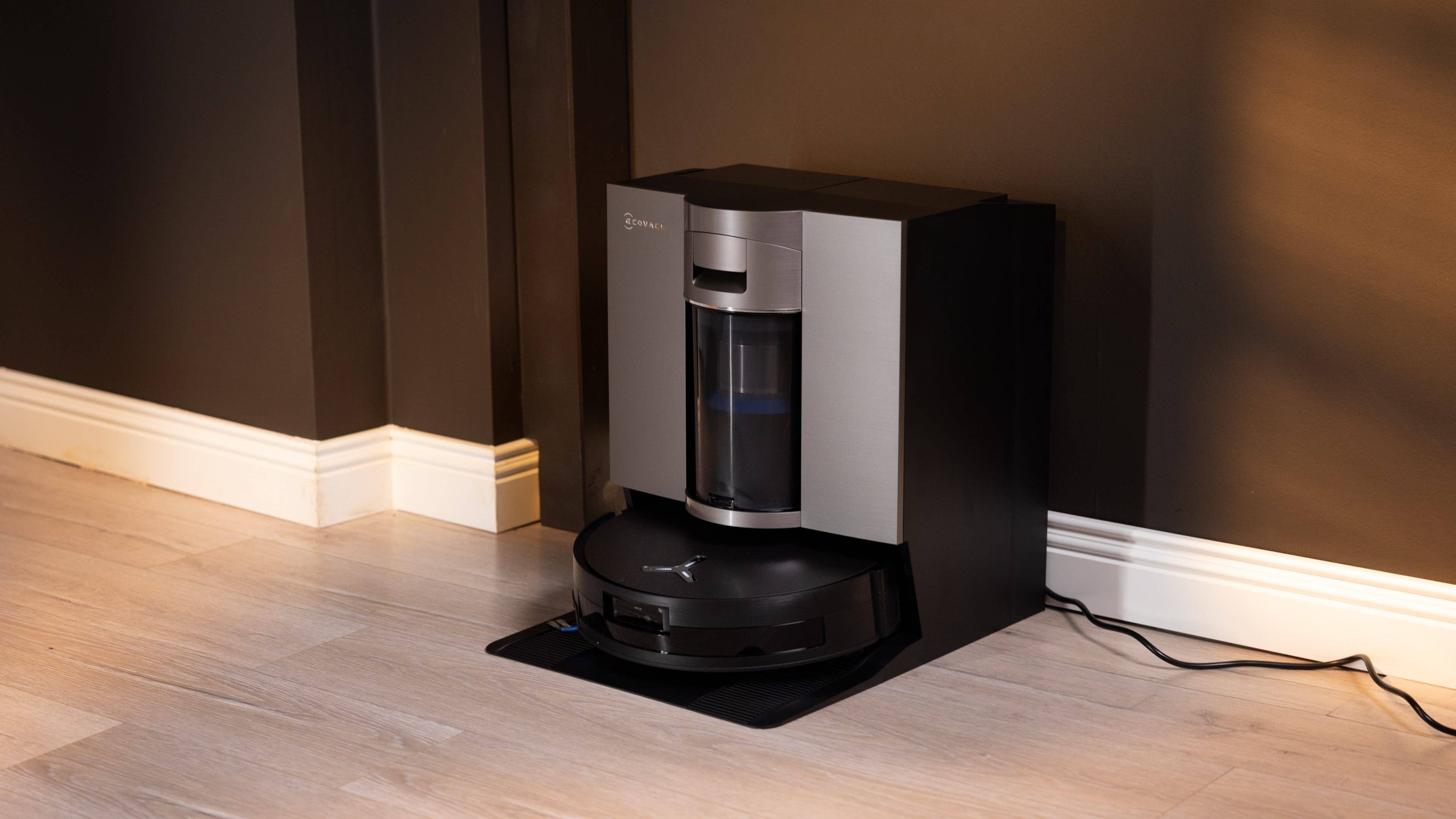 Moderne Ecovacs Deebot X11 Omniclone Saugroboter, angedockt an einer dunklen Wand.