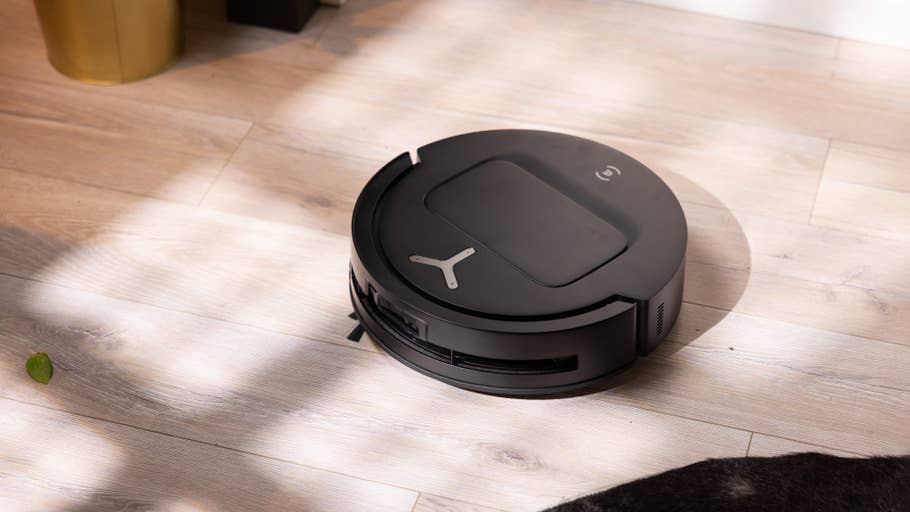 Schwarzer Ecovacs T80 Omni-Roboterstaubsauger auf holzfarbener Fläche mit sanften Schatten.