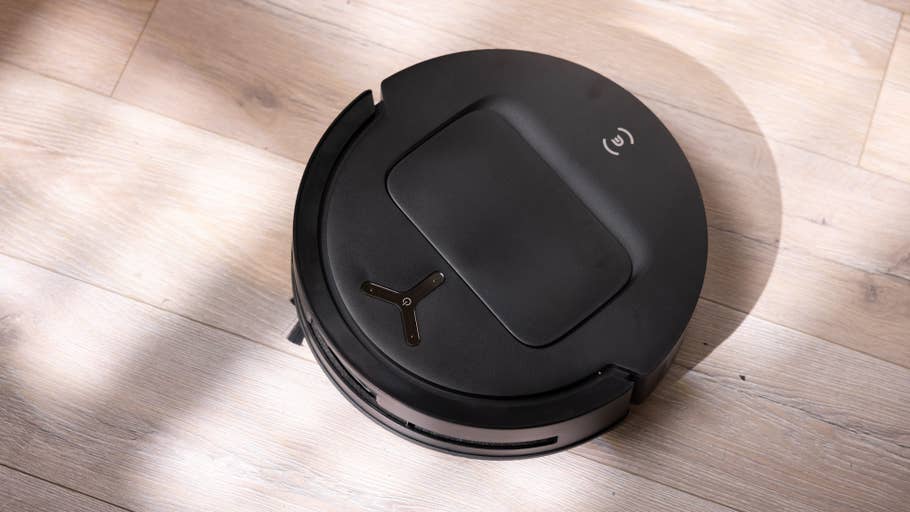 Schwarzer Roboterstaubsauger auf einem Holzboden.