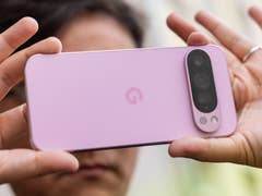 Eine Person hält ein Google Pixel 9 Pro-Smartphone, das seine Rückseite in sanfter rosa Farbe zeigt.