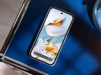 Ein Google Pixel 9a Smartphone auf einer blauen Oberfläche neben einer blauen Lampe.