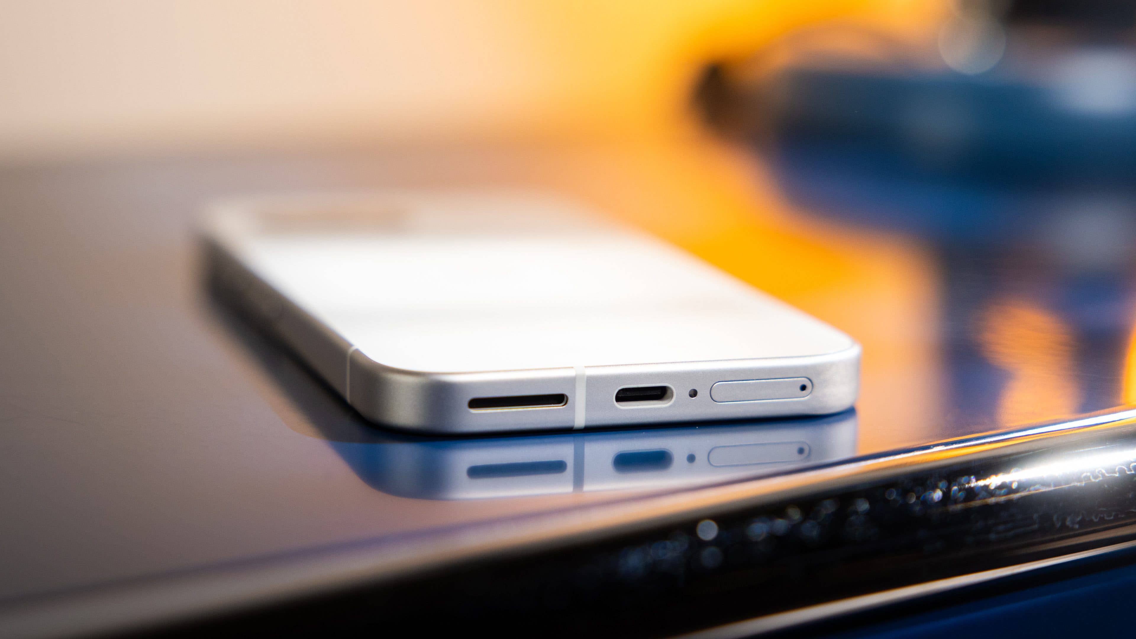 Nahaufnahme der Anschlüsse eines Google Pixel 9a Smartphones auf einer reflektierenden Oberfläche.