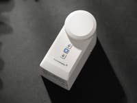 Ein weißes Homematic IP Smart Lock mit einer runden Oberseite und zwei Tasten an der Seite.