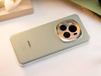 Ein auf der Rückseite liegendes Smartphone zeigt die strukturierte grüne Oberfläche und das kreisförmige Kameramodul mit einem dezenten Markenaufdruck an der Unterseite.