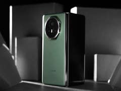 Ein schlanker grüner Smartphone mit einer runden Kamera auf einem dunklen Hintergrund.