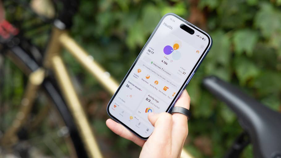 Eine Person hält ein Smartphone, das Gesundheitsstatistiken anzeigt, mit einem Fahrrad im Hintergrund.