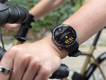 Eine Nahaufnahme einer Huawei Watch GT 6 Pro am Handgelenk einer Person, die einen Fahrradlenker hält.