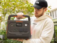 Eine Person hält einen Jackery Explorer 1000 v2 tragbaren Stromgenerator im Freien.